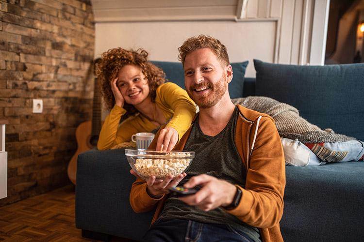 Mann und Frau essen Popcorn vor dem TV