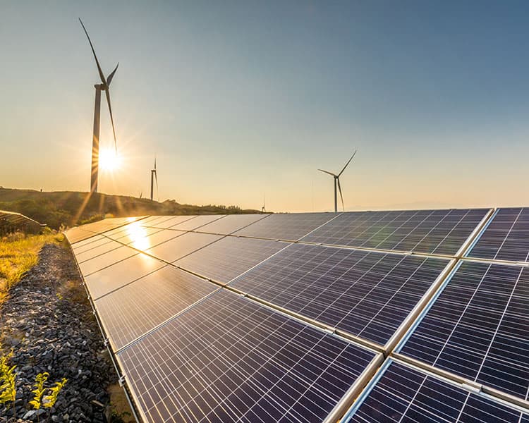 Photovoltaikanlage auf einem Feld und Windanlagen im Hintergrund