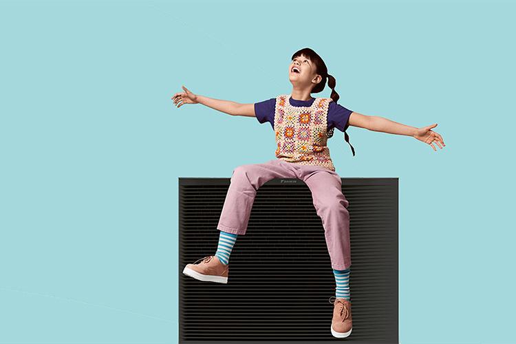 Mädchen sitzt mit ausgebreiteten Armen auf einer Wallbox