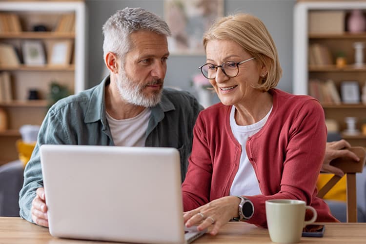 Frau und Mann sitzen gemeinsam zuhause vor einem Laptop.
