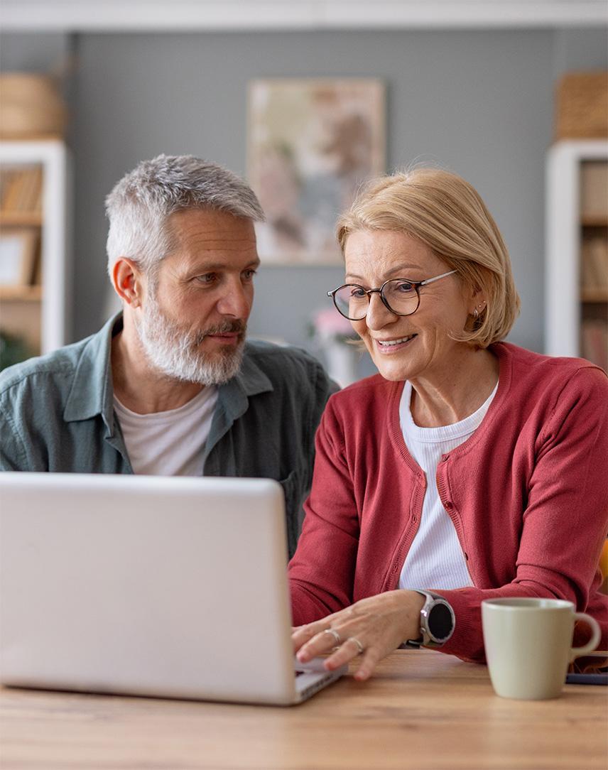 Frau und Mann sitzen gemeinsam zuhause vor einem Laptop.