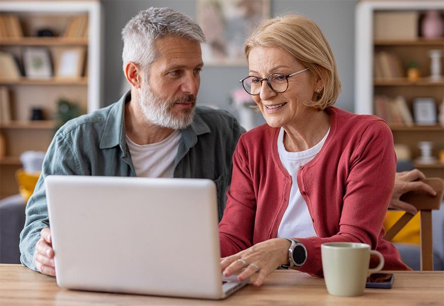 Frau und Mann sitzen gemeinsam zuhause vor einem Laptop.