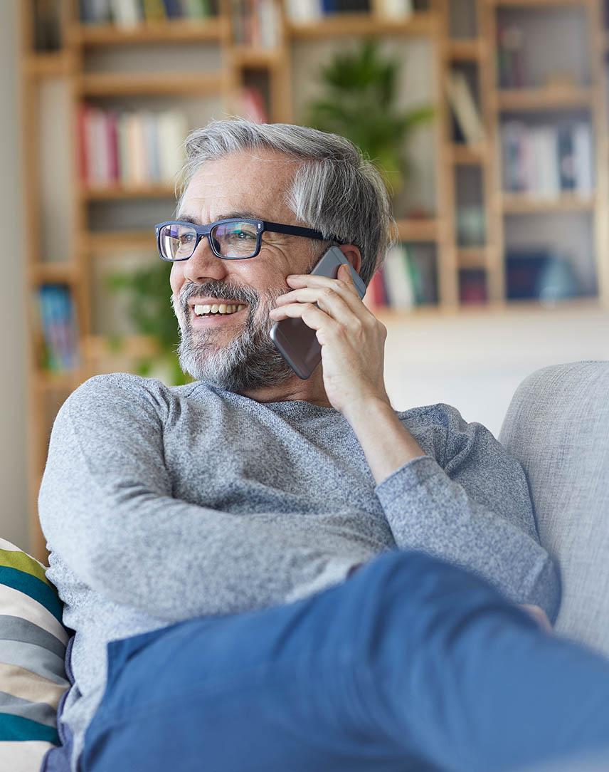 Mann auf dem Sofa telefoniert mit dem Smartphone.