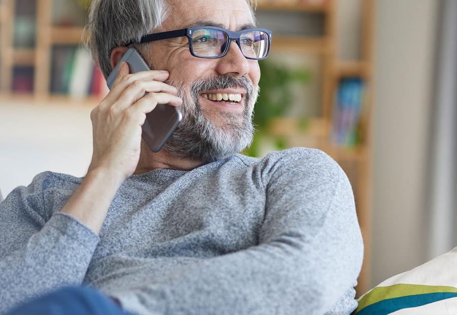 Mann auf dem Sofa telefoniert mit dem Smartphone.