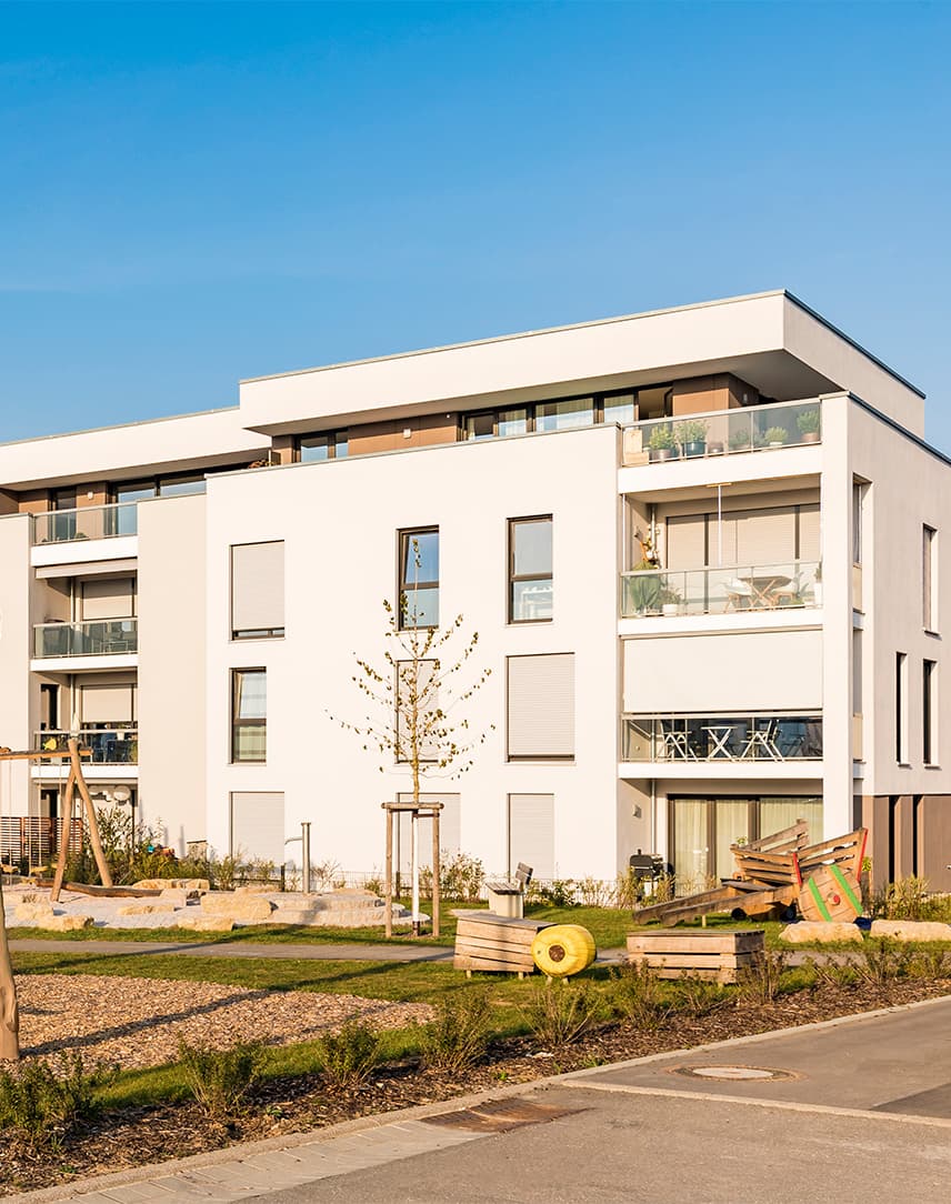 Eine Mehrfamilienhaussiedlung mit Spielplatz.